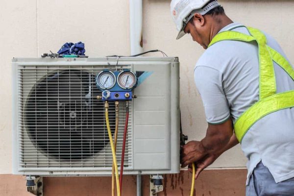 a professional electrician man is fixing a heavy air conditioner. Model is actual repairman electrician. Air Conditioning Repair.