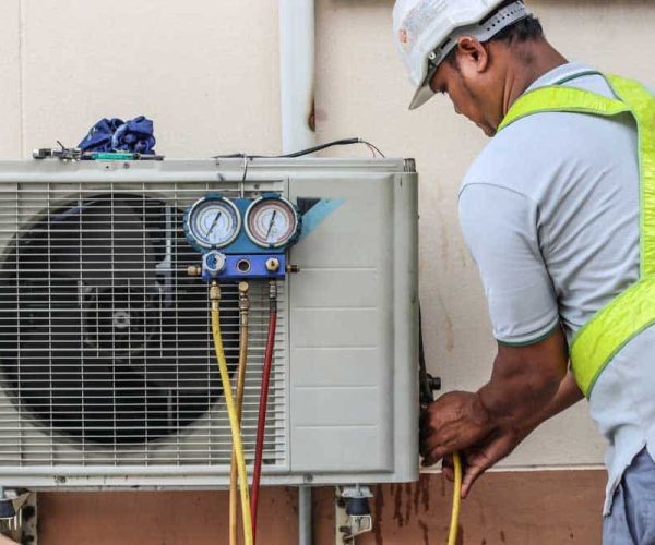 a professional electrician man is fixing a heavy air conditioner. Model is actual repairman electrician. Air Conditioning Repair.